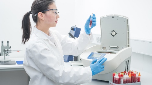 Scientist Loading Sigma 1-7 laboratory benchtop centrifuge with collection of blood tubes